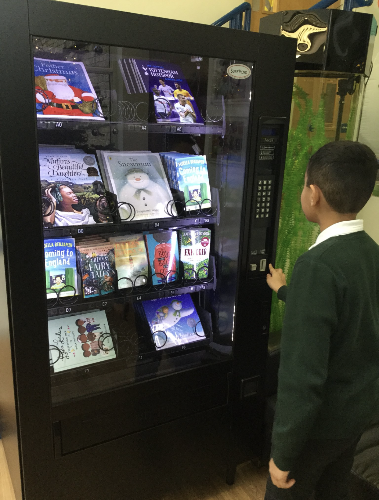 child using token to get a book from book vending machine